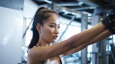 年轻的亚洲女士在健身课上做运动机械电缆交叉体脂燃烧锻炼。运动员六包，女运动员娱乐活动，功能性训练，健康的生活方式.